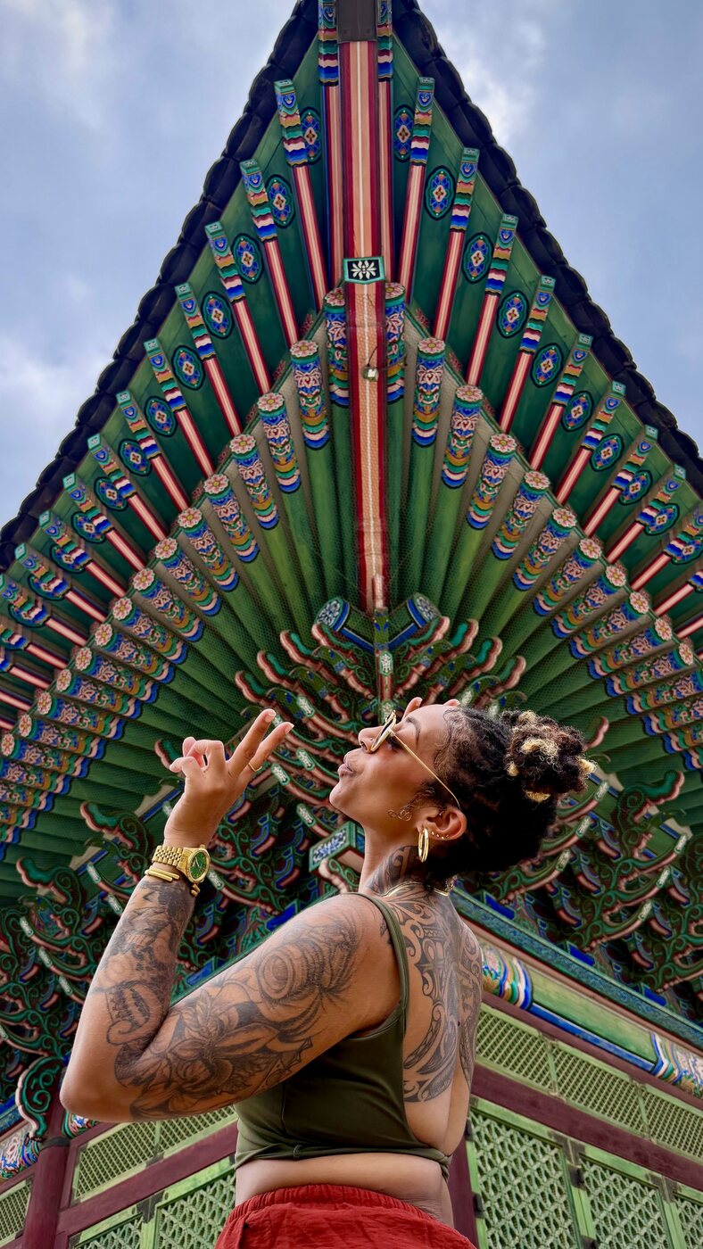 Ashleigh Bing looking up at a colorful Korean pagoda ceiling