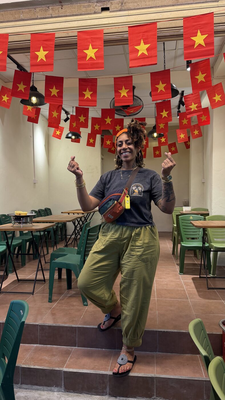 Ashleigh Bing posing playfully under Vietnamese flags